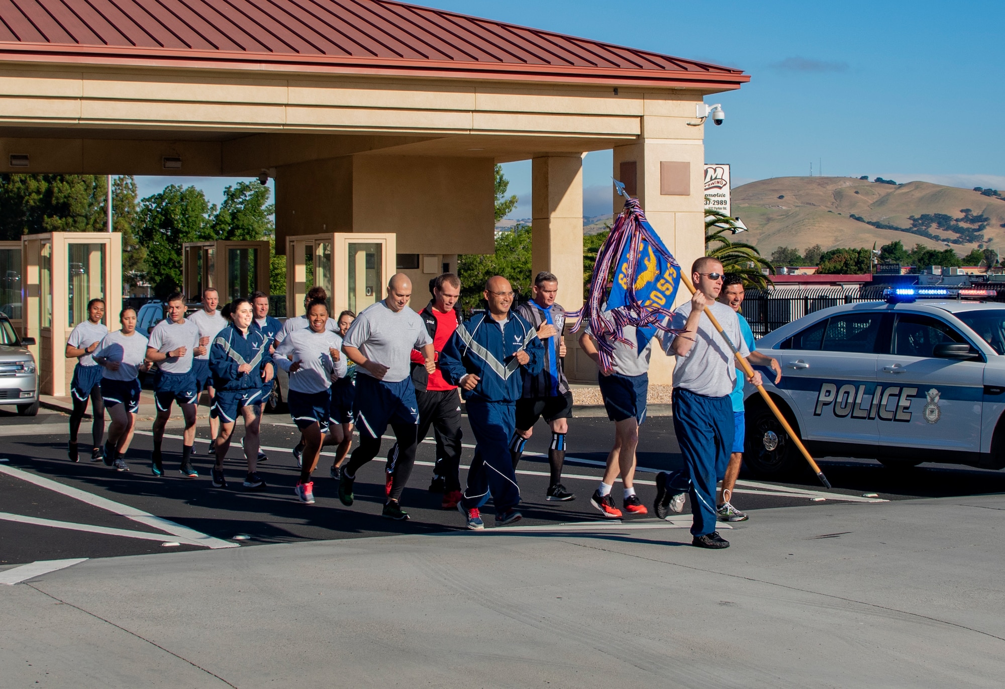 U.S. Air Force Tech. Sgt. Mark Henry, 60th Security Forces Squadron flight chief, holds a guidon as he leads fellow 60th SFS defenders and athletes from Solano County through the main gate during the Northern California Law Enforcement Torch Run June 20, 2019, at Travis Air Force Base, California Hundreds of Law Enforcement personnel from northern California escorted the Special Olympics torch, the Flame of Hope, throughout their local communities in a relay to the 2019 Special Olympics Northern California Summer Games, being held at the University of California Davis campus June 21-23. (U.S. Air Force photo by Heide Couch)