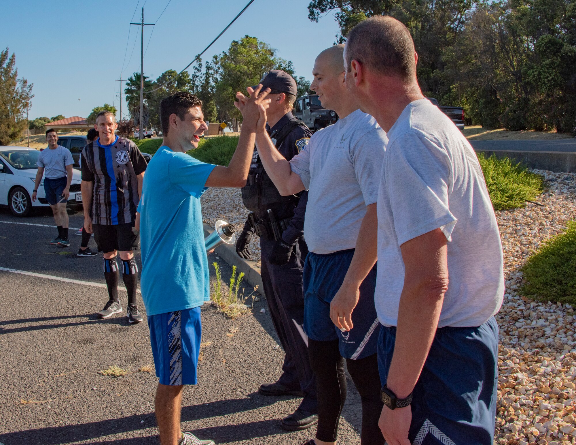 U.S. Air Force 60th Security Forces Squadron defenders congratulate Erick Silva at the completion of their portion of the Northern California Law Enforcement Torch Run June 20, 2019, at Travis Air Force Base, California. Hundreds of Law Enforcement personnel from northern California escorted the Special Olympics torch, the Flame of Hope, throughout their local communities in a relay to the 2019 Special Olympics Northern California Summer Games, being held at the University of California Davis campus June 21-23. (U.S. Air Force photo by Heide Couch)