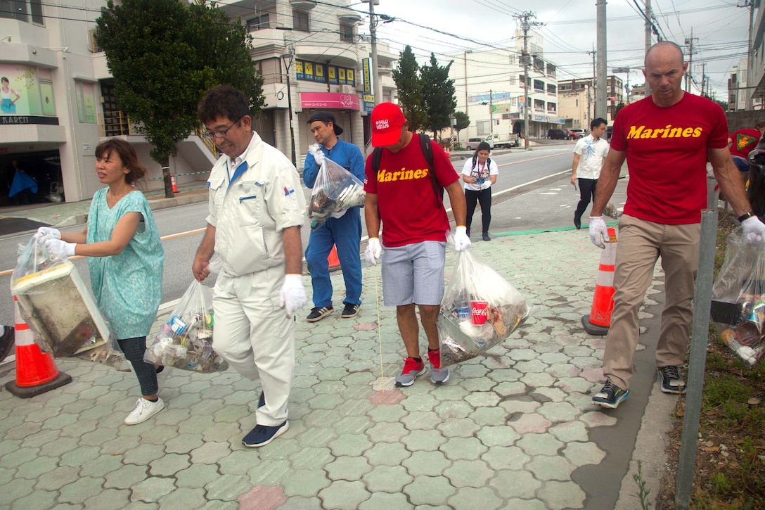 宜野湾市住民と普天間基地の海兵隊員らがボランティアで6月19日、沖縄コンベンションセンター周辺の清掃活動をしました。ボランティアたちは道路沿いにある茂みの中や側溝の中、側溝のふたの下にあるゴミなども拾いました。