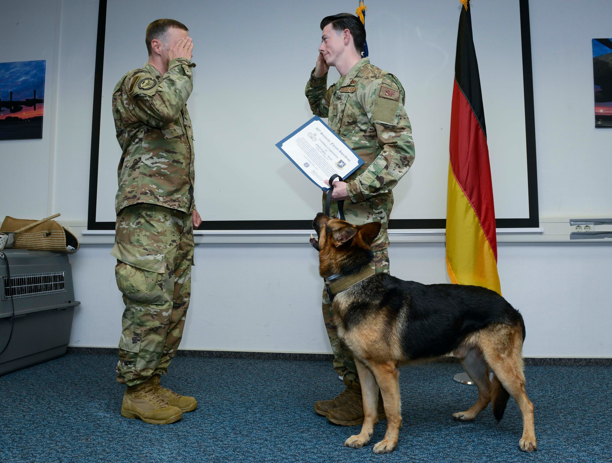 U.S. Air Force Senior Airman Jonathan Engle, right, 86th Security Forces Squadron military working dog handler, accepts a certificate of appreciation from Lt. Col. Erik Dutkiewicz, 86th SFS commander, on behalf of Vulcan, 86th SFS MWD, during Vulcan’s retirement ceremony at Ramstein Air Base, Germany, May 18, 2019. The 86th SFS honors its retiring canines with ceremonies comparable to those Airmen receive, including the singing of the national anthem, a speech highlighting the animal’s service achievements, and honored guests in attendance.