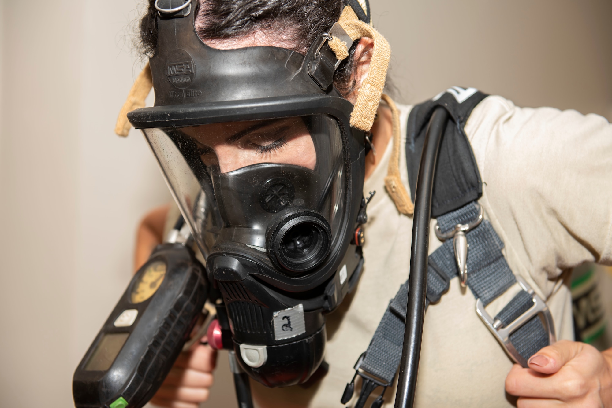 U.S. Air Force Staff Sgt. Carola Ansleny, 20th Medical Group bioenvironmental technician, dons her oxygen tank as part of the process for putting on a Hazardous material (HAZMAT) suit, at Shaw Air Force Base, South Carolina, June 18, 2019.