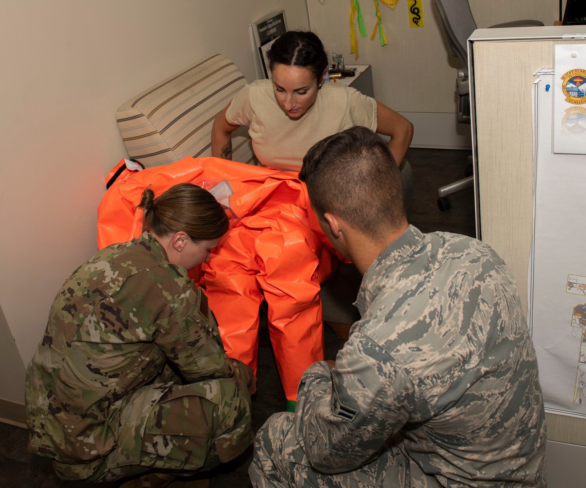 U.S. Air Force Staff Sgt. Carola Anslemi, 20th Medical Group bioenvironmental technician, center, receives help form her colleagues putting on a hazardous material suit at Shaw Air Force Base, South Carolina, June 18, 2019.