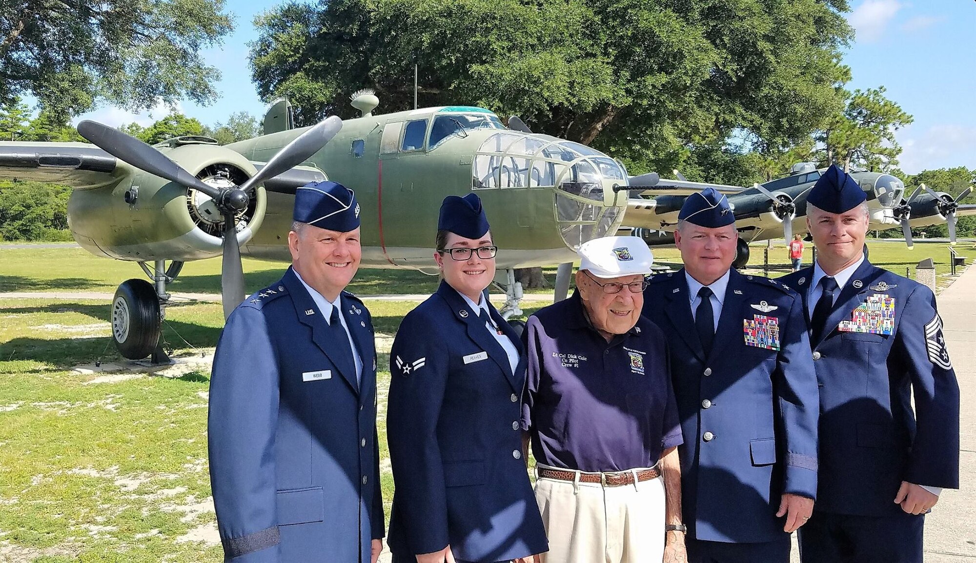 Five people standing together in front of an aircraft.