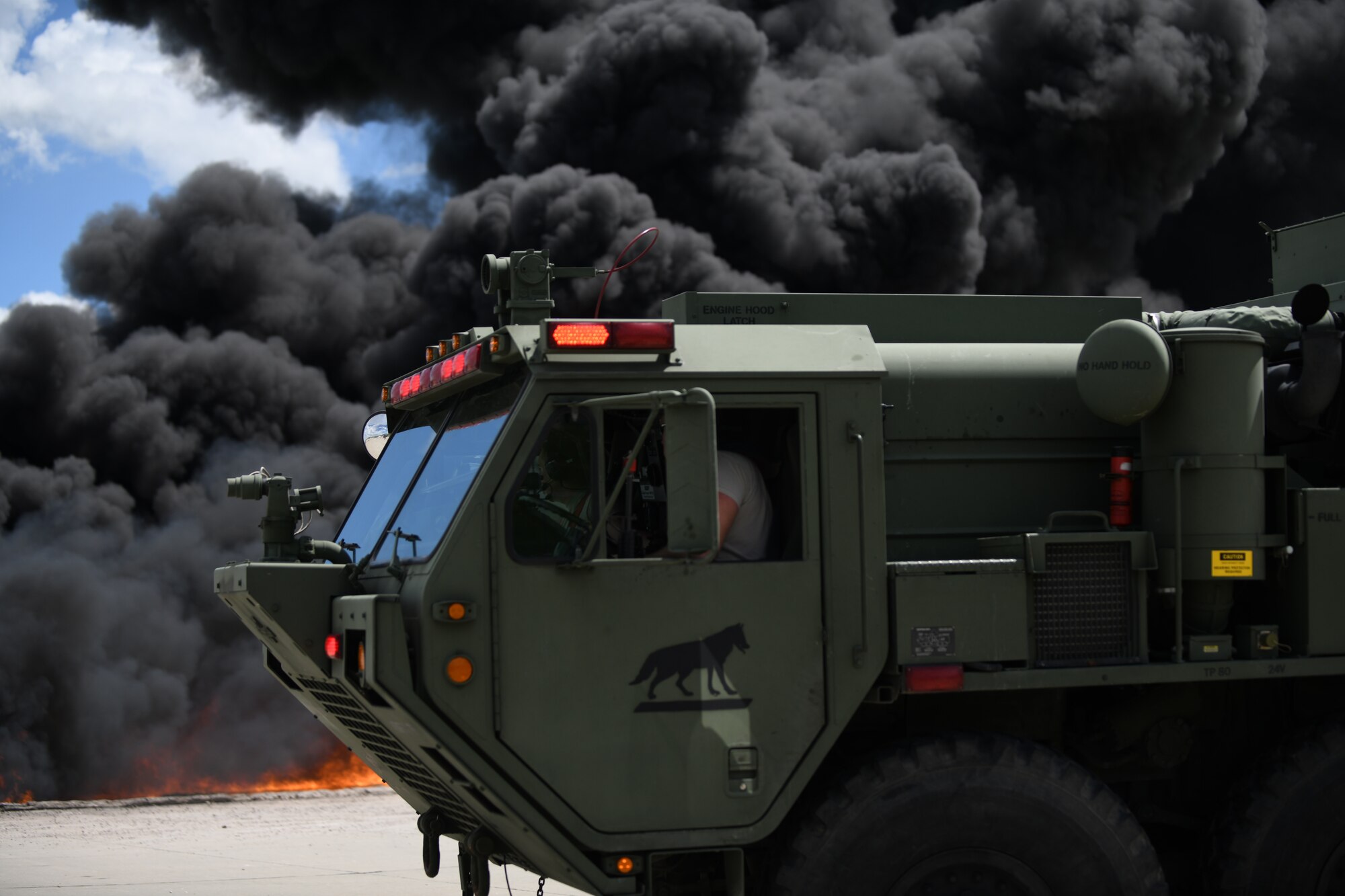A firetruck from South Dakota’s National Guard prepares to extinguish a mock aircraft fire at Ellsworth Air Force Base, S.D., June 12, 2019. For larger fires, fire trucks drive around the fire pit and use turrets connected to the fire truck to extinguish the flames. (U.S. Air Force photo by Airman 1st Class Christina Bennett)