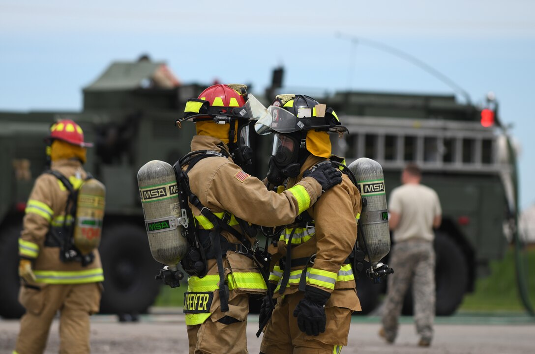 Firemen from Nebraska’s Army National Guard perform a buddy check after extinguishing a handline fire at the training facility at Ellsworth Air Force Base, S.D., July 13, 2019. During the training, safety is paramount. Firemen are swapped out after every iteration and all equipment is reassessed to reduce the risk of safety incidents. (U.S. Air Force photo by Airman 1st Class Christina Bennett)