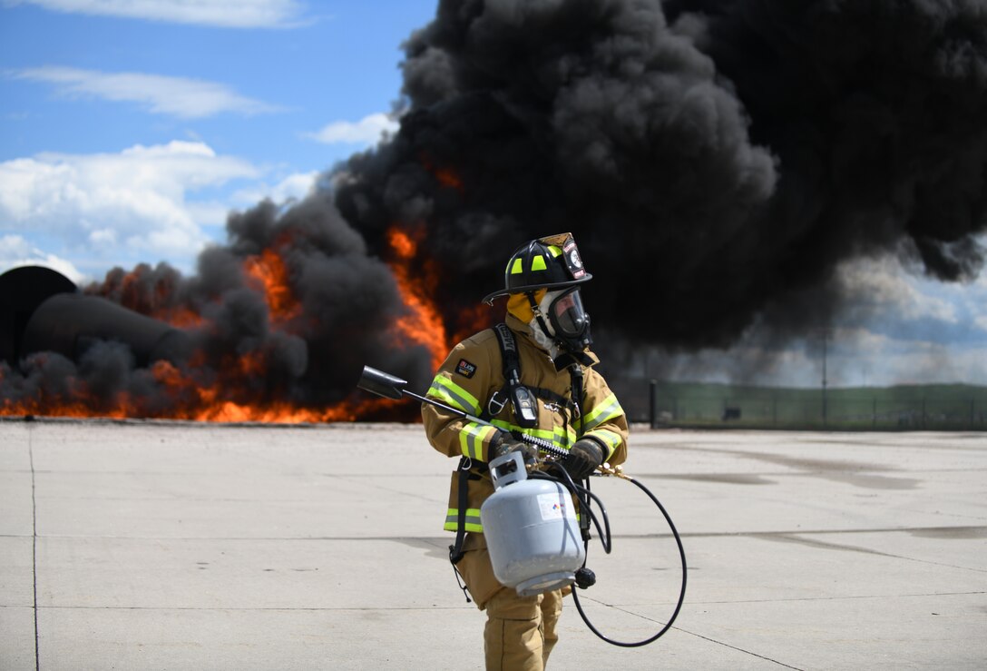 A firefighter from South Dakota’s Army National Guard carries a light torch after igniting the fuel pit at Ellsworth Air Force Base, S.D., June 12, 2019. The fire pit at Ellsworth AFB provides Guardsmen with a realistic training experience due to its use of jet fuel, rather than the standard use of propane. (U.S. Air Force photo by Airman 1st Class Christina Bennett)