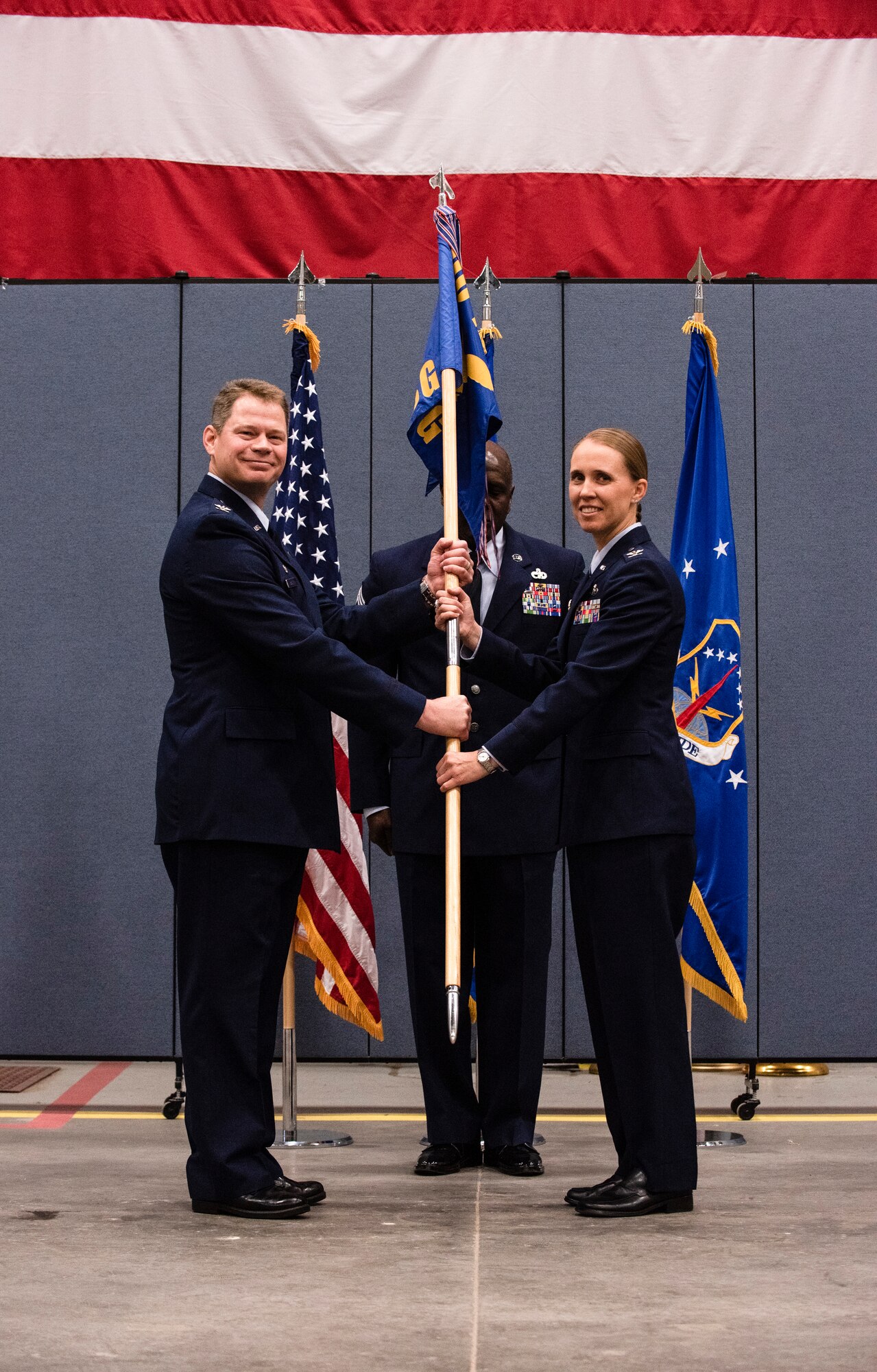 Colonel Peter Bonetti, 90th Missile Wing commander, passes the guidon to Col. Carolyn Ammons, 90th Mission Support Group incoming commander, during the 90th MSG assumption-of-command ceremony Jun 21, 2109, on F.E. Warren Air Force Base, Wyo. An assumption of command ceremony is a tradition that represents a formal transfer of authority and responsibility to the incoming commander. (U.S. Air Force photo by Senior Airman Abbigayle Williams)