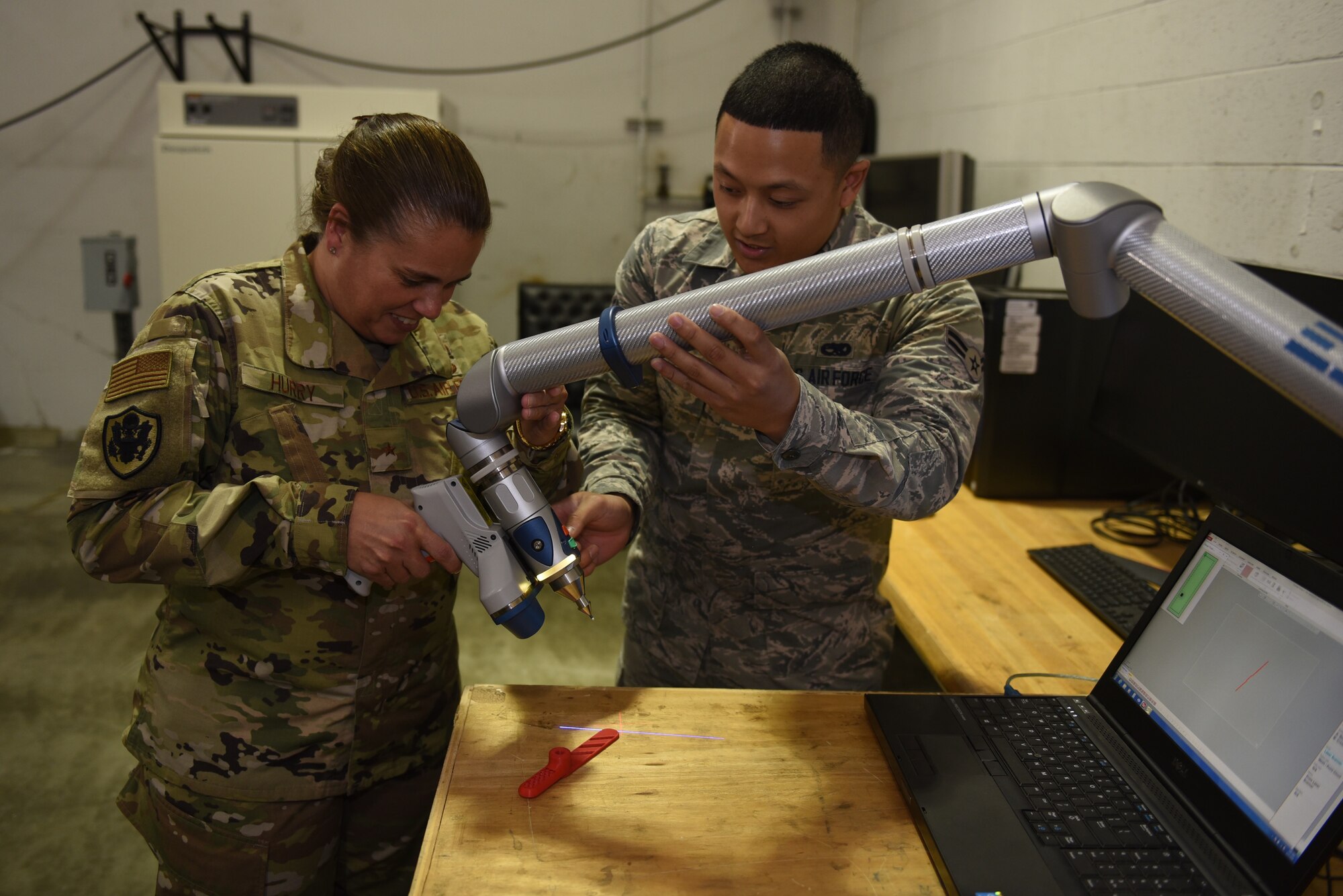 U.S. Air Force Airman 1st Class Leander Monte, 60th Maintenance Squadron aircraft metal technologist, shows Brig. Gen. Linda Hurry, Defense Logistics Agency Aviation commander, how aircraft parts are made with 3D printing June 17, 2019, at Travis Air Force Base, California. The local 3D printers help mitigate slow supply issues. DLA Aviation is the combat logistics and supply chain manager for aviation and nuclear assets across the Department of Defense. (U.S. Air Force photo by Airman 1st Class Cameron Otte)