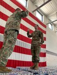 Maj. Drew Polen (left), executive officer of the 891st Engineer Battalion, gives the reenlistment oath to Spc. Russell O'Neill (right), assigned to 891st Forward Support Company, June 2, a top of pallets of water that are ready to be distributed to communities in Kansas devastated by flooding in May.