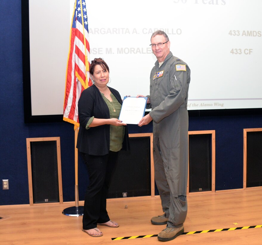Col. Terry W. McClain, 433rd Airlift Wing commander, presents a 30-year service award certificate to Margie Carrillo, 433rd Aerospace Medicine Squadron administrative assistant, June 20, 2019 at Joint Base San Antonio-Lackland, Texas.