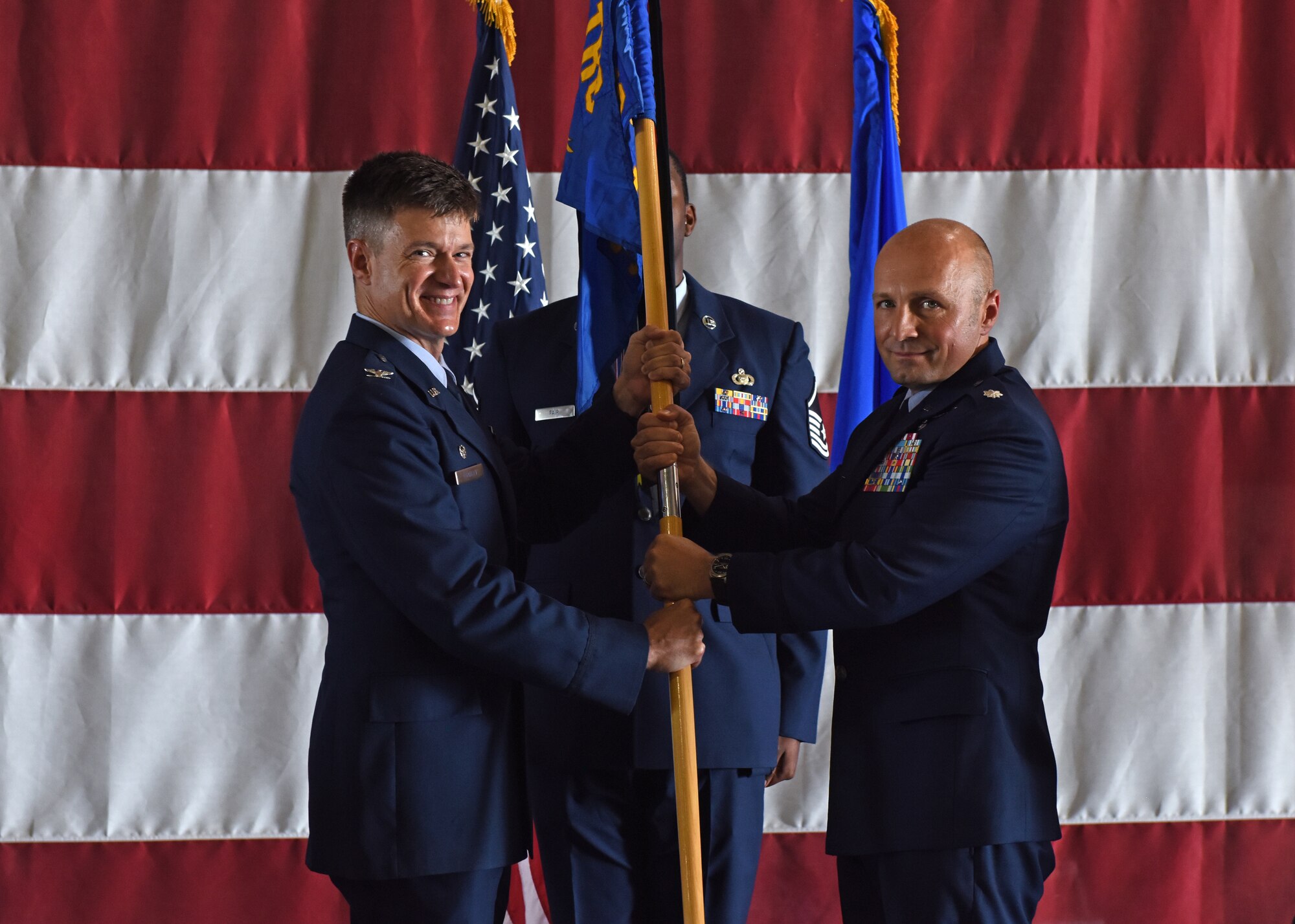 U.S. Air Force Col. Thomas Coakley, 17th Training Group commander, passes the guidon to Lt. Col. Christopher Sharp, incoming 316th Training Squadron commander, during the change of command ceremony at the Louis F. Garland Department of Defense Fire Academy High Bay on Goodfellow Air Force Base, Texas, June 21, 2019. Sharp has served in diverse assignments, such as an instructor here, Information Integration Officer aboard RC-135 V/W Rivet Joint aircraft, Intelligence Weapons Officer supporting U-2, RQ-4 Global Hawk and MC-12 aircraft, and as the Wing Senior Intelligence Officer supporting F-15E Strike Eagle operations. (U.S. Air Force photo by Airman 1st Class Zachary Chapman/Released)