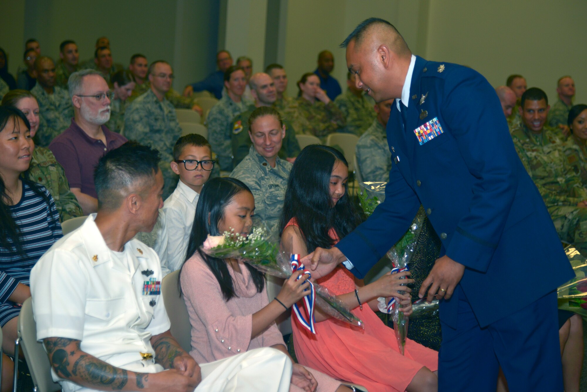 U.S. Air Force Lt. Col. Elbert G. Mose, incoming 81st TRSS commander, hands out flowers to his family members during the 81st TRSS change of command ceremony in the Roberts Consolidated Aircraft Maintenance Facility on Keesler Air Force Base, Mississippi, June 20, 2019. Mose assumed command from Lt. Col. Stephen P. Arnott with the passing of the guidon. The passing of the guidon is a ceremonial symbol of exchanging command from one commander to another. (U.S. Air Force photo by Airman Seth Haddix)