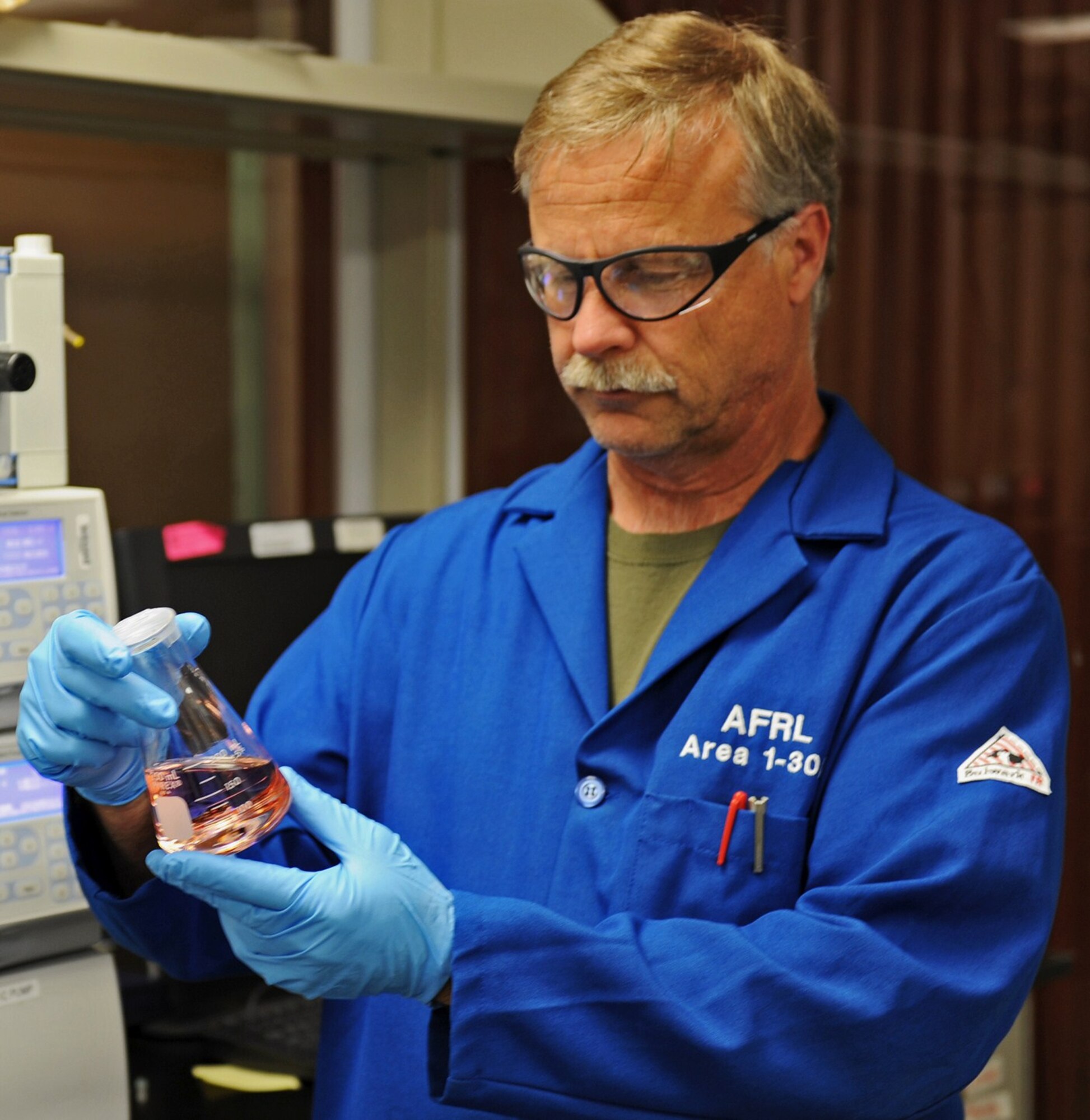 Milton McKay, a research chemist from the Air Force Research Laboratory’s Rocket Propulsion Division at Edwards AFB, California, examines a sample of the AFRL developed ASCENT (Advanced Spacecraft Energetic Non-toxic Propellant) green propellant. (Courtesy photo)