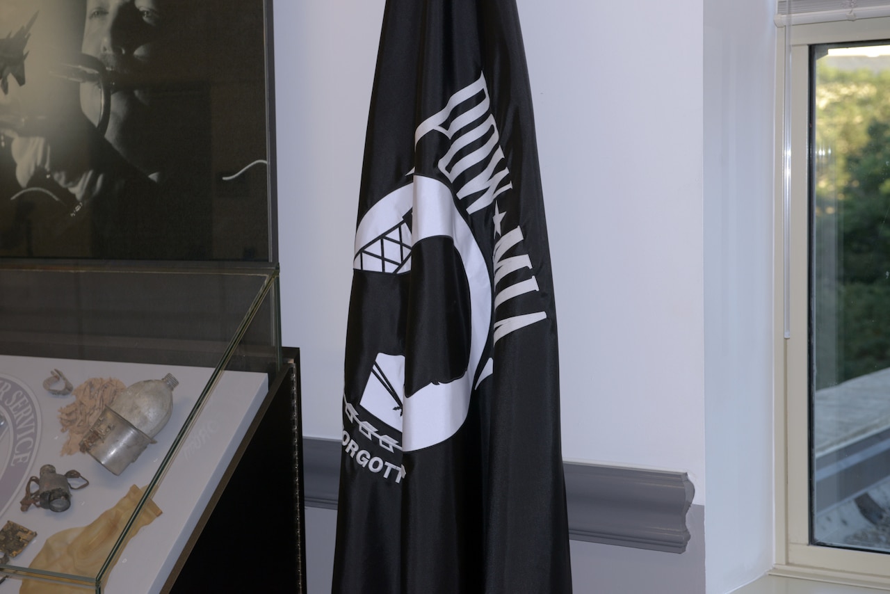 A furled black flag bears the letters “POW/MIA.”