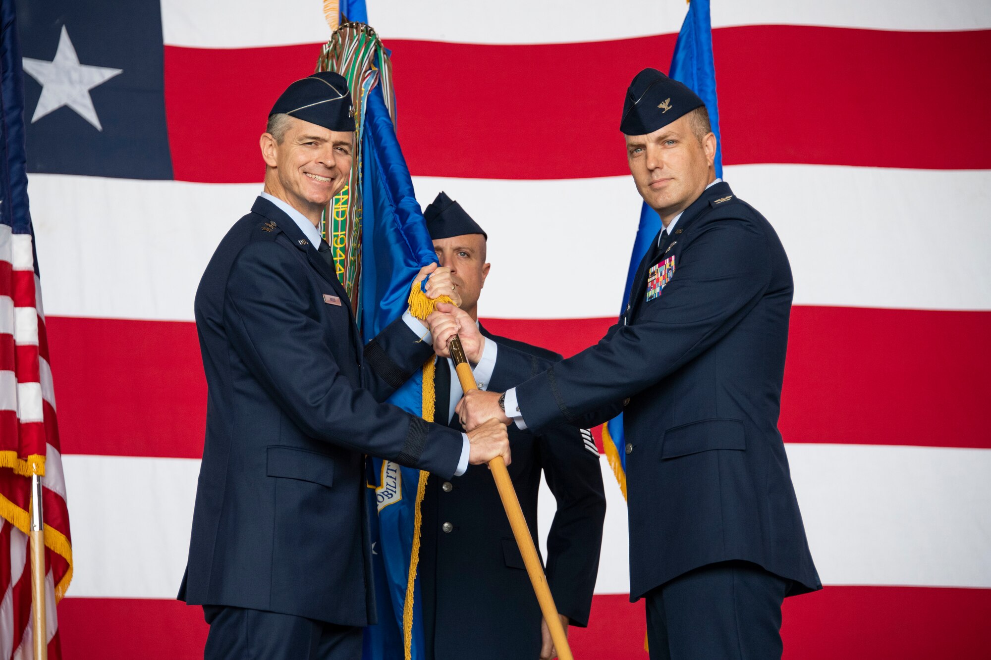 U.S. Air Force Maj. Gen. Craig Wills, 19th Air Force commander, passes the guidon to U.S. Air Force Col. Matthew Leard, 97th Air Mobility Wing commander, during the 97th AMW change of command ceremony, June 21, 2019, at Altus Air Force Base, Okla. Leard assumed command from U.S. Air Force Col. Eric Carney and is responsible for the formal training of all KC-135 Stratotanker, C-17 Globemaster III and KC-46 Pegasus aircrews for active duty, Air National Guard, Air Force Reserve units as well as multiple partner air forces from across the world. (U.S. Air Force photo by Airman 1st Class Breanna Klemm)