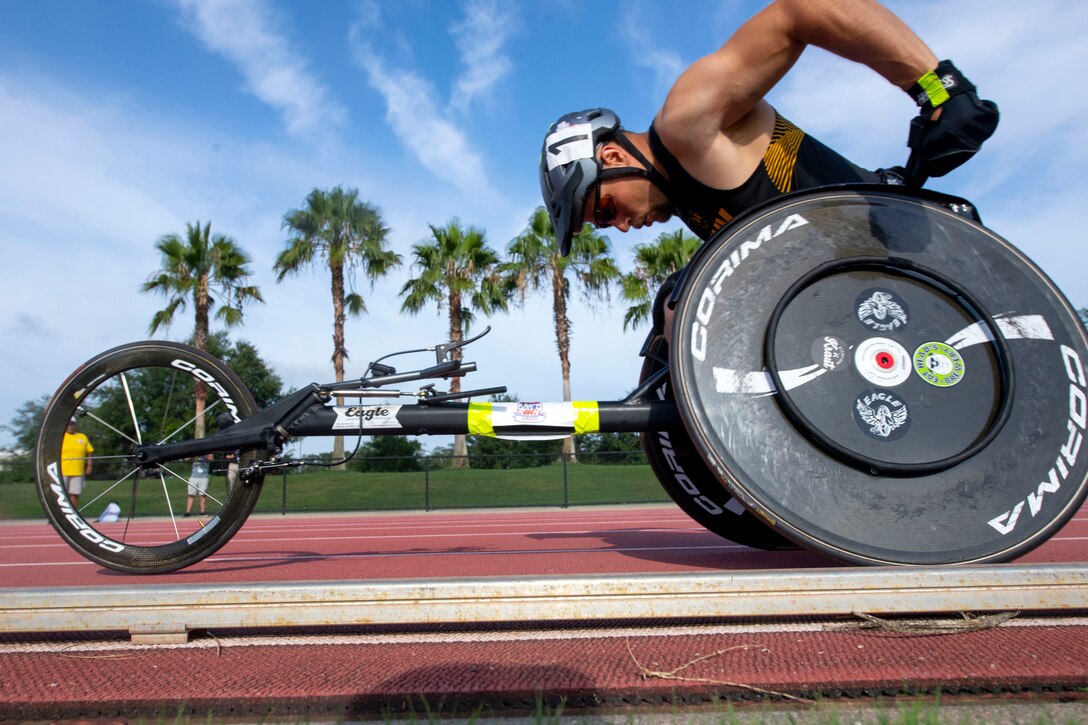 An athlete drives a racing wheelchair on a track.