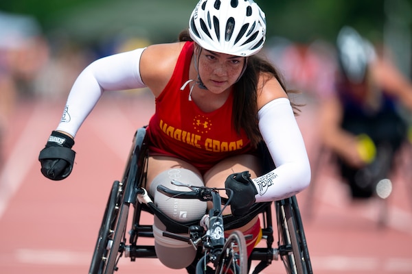 A female wheelchair racers drives towards the finish line during the 2019 Warrior Games.