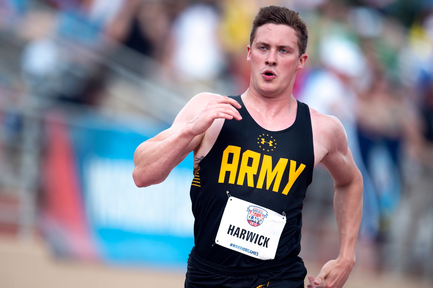 A male runner wearing a black Army shirt sprints during the Warrior Games.