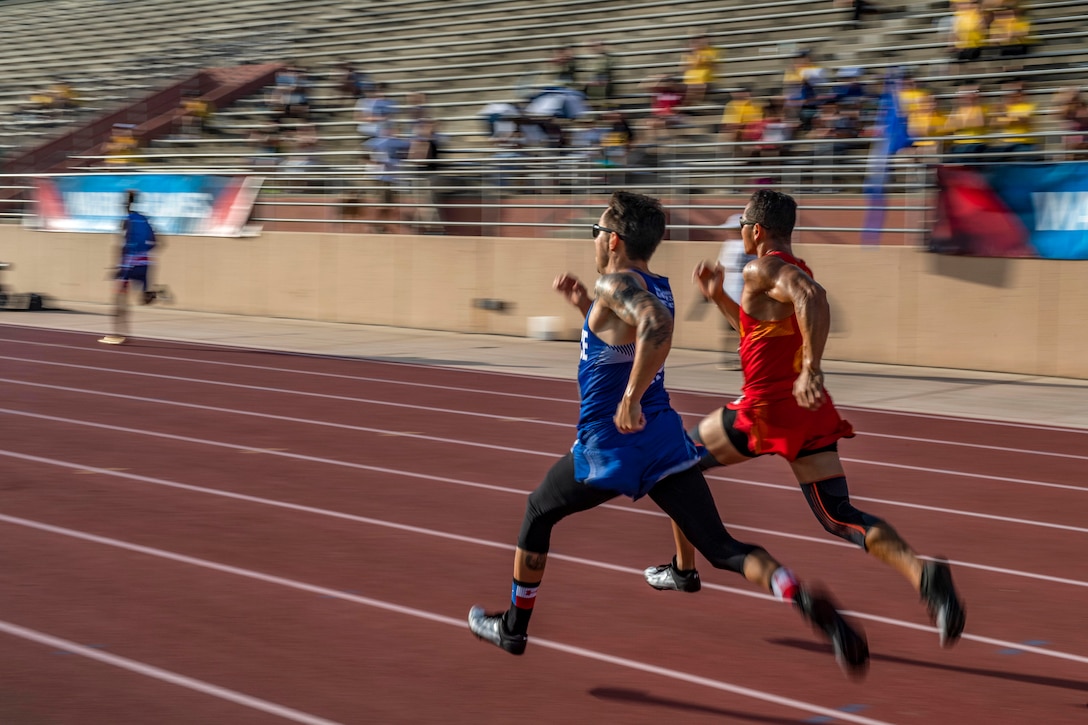 Two runners race side-by-side on a track, their strides mirroring each other.