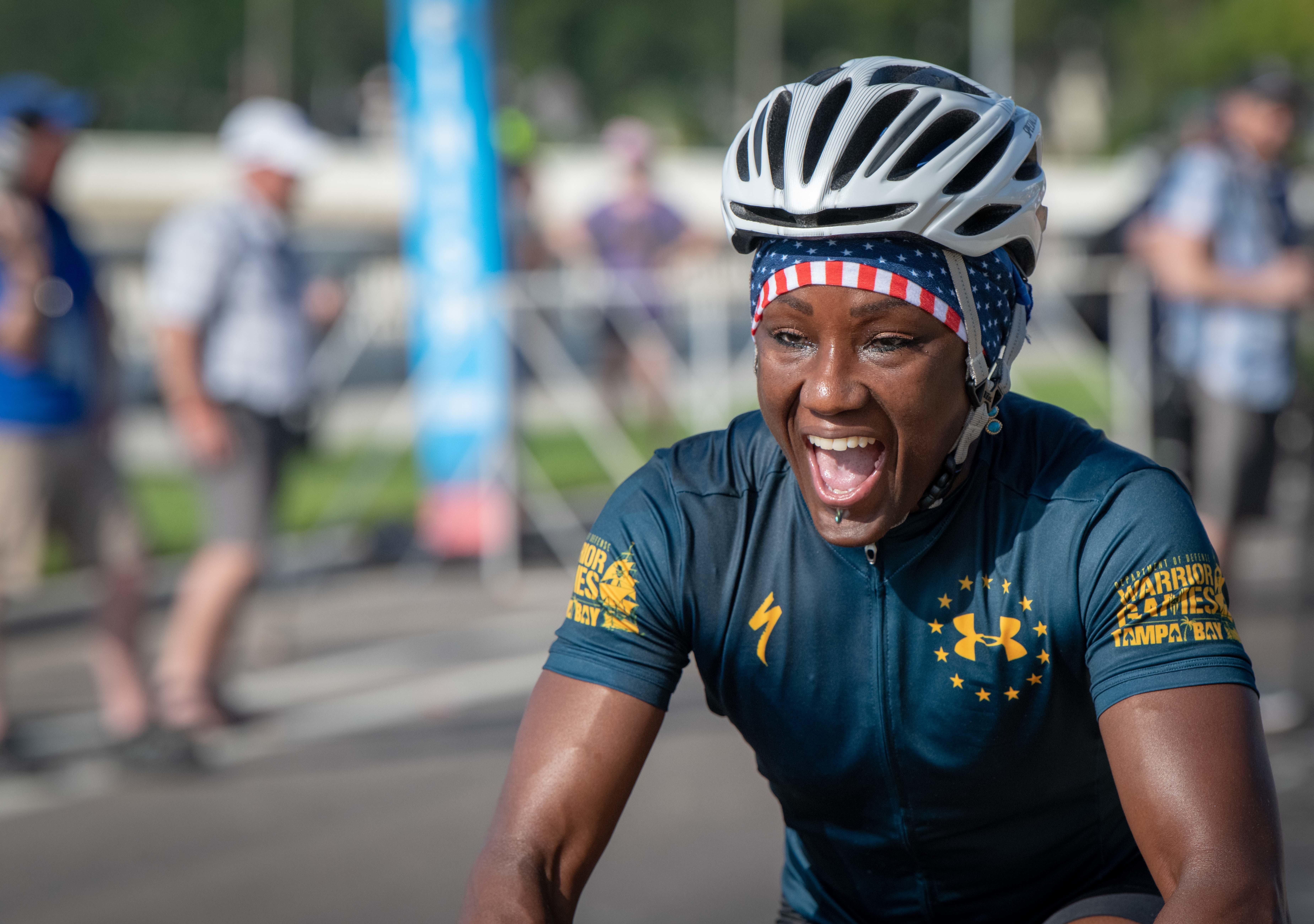 An African American woman smiles while biking during the cycling time trials for Team Navy during the 2019 DoD Warrior Games in Tampa, Florida.