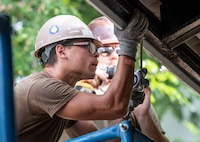 U.S. Navy Steelworker Constructionman Joseph Synowiec, assigned to Naval Mobile Construction Battalion (NMCB) 4, uses a tape measure to determine where members of the Royal Thai Armed Forces will place a gutter at the Ban Surasak School project site during Pacific Partnership 2019. (Mass Communication Specialist 2nd Class Kelsey L. Adams)