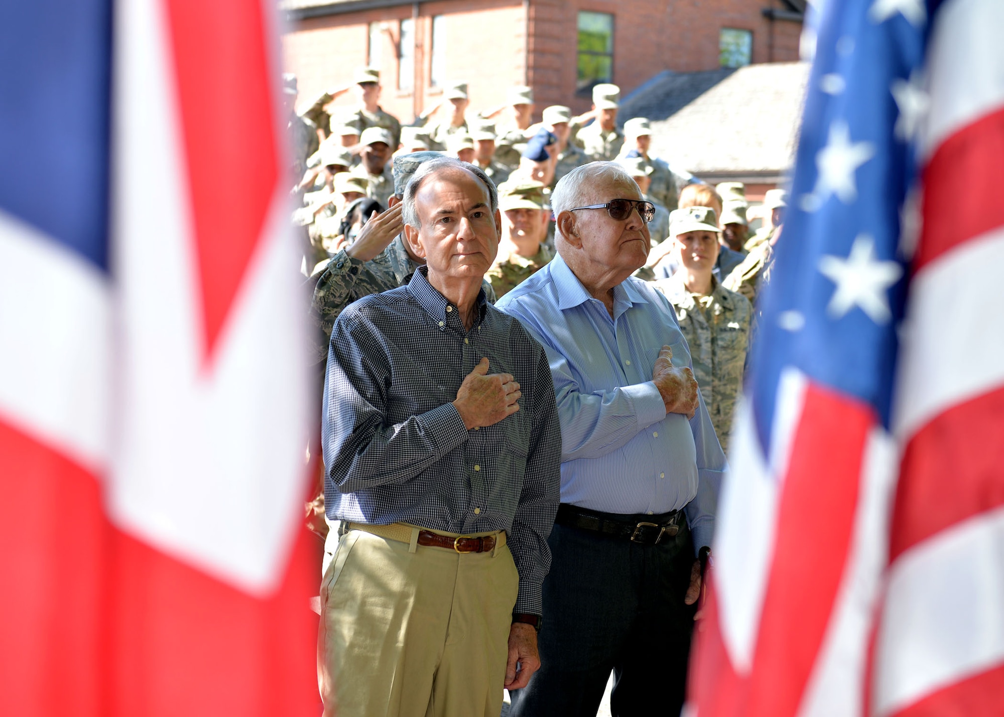 Retired Master Sgt. Dewey Christopher, right, and his son Gary, stand with their hands over their hearts during the playing of the national anthem at the Professional Development Center renaming ceremony on RAF Mildenhall, June 21. 2019. Dewey, a former 351st Bomb Squadron crew chief, 100th Bomb Group and World War II veteran, visited the base for the ceremony renaming the PDC in his honor. (U.S. Air Force photo by Karen Abeyasekere)