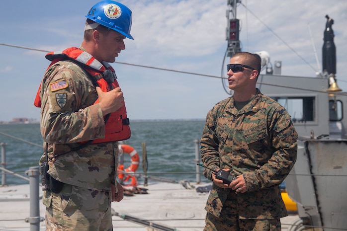 U.S. Marine Corps 2nd Lt. Justin Machacek, left, a platoon commander with 2nd Transportation Support Battalion, Combat Logistics Regiment 2, 2nd Marine Logistics Group, speaks with Army Sgt. 1st Class Enrique Mendiet, 11th Transportation Battalion, 7th Transportation Regiment, during the off load of the USNS Watkins (T-AKR-315) as part of exercise Resolute Sun at Fort Story, V.A., June 18, 2019. Marines participated in the exercise to increase combat operational readiness in amphibious and prepositioning operations while conducting joint training with the U.S. Army during a joint logistics over the shore scenario. (U.S. Marine Corps photo by Lance Cpl. Scott Jenkins)