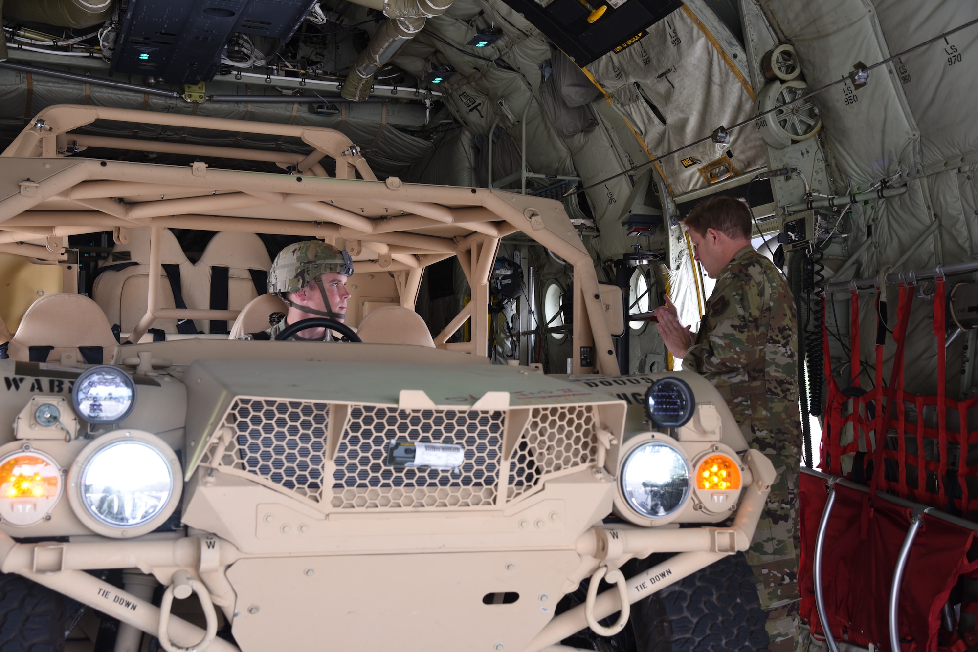 Senior Master Sgt. Eric Gassiot, a loadmaster with the 815th Airlift Squadron, 403rd Wing, explains the procedures for vehicle operations to Corporal Jared Guden, 82nd Airborne, scout platoon team leader, after he drove a ground mobility vehicle onto a C-130J in preparation for exercise Swift Response 19, June 14, 2019. The exercise is one of the premier military crisis response training events featuring high readiness airborne forces from eight NATO nations. Activities include intermediate staging base operations, multiple airborne operations, and several air assault operations. The Swift Response exercises have had great success in creating a foundation for the strong relationships we share with several European allies and partners today. (U.S. Air Force photo by Master Sgt. Jessica Kendziorek)