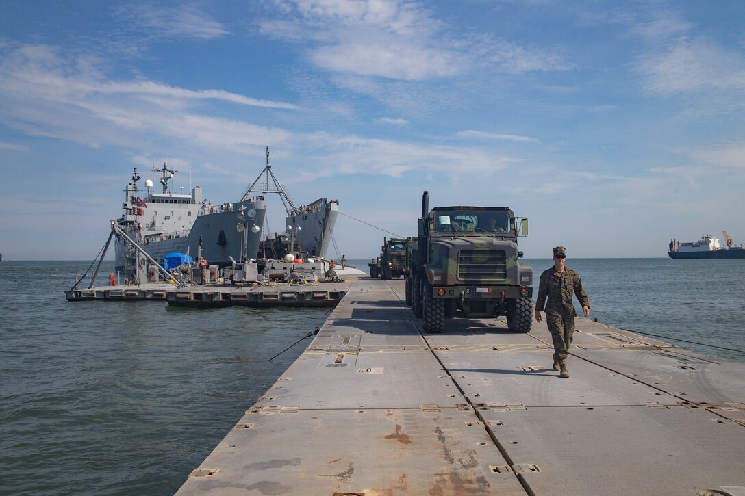 U.S. Marines with 2nd Transportation Support Battalion, Combat Logistics Regiment 2, 2nd Marine Logistics Group, ground guide vehicles down a trident pier during the off load of the USNS Watkins (T-AKR-315) during exercise Resolute Sun at Fort Story, V.A., June 18, 2019. U.S. Marines participated in the exercise to increase combat operational readiness in amphibious and prepositioning operations while conducting joint training with the U.S. Army during a joint logistics over the shore scenario. (U.S. Marine Corps photo by Lance Cpl. Scott Jenkins)