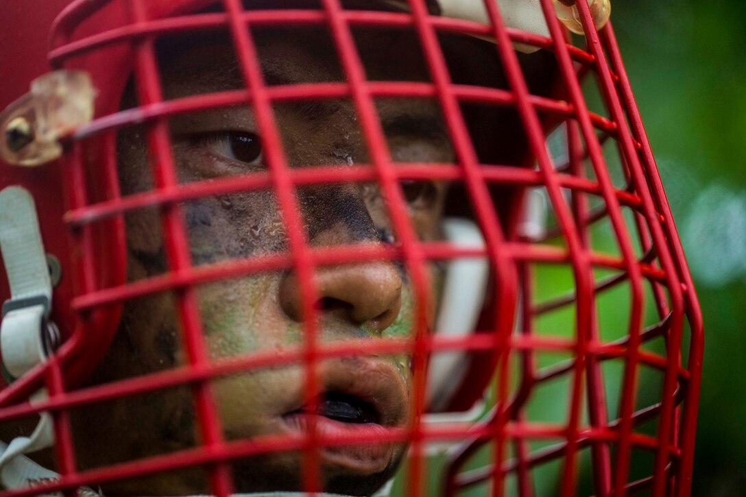 A close up of a Marine wearing a helmet with a red face mask.