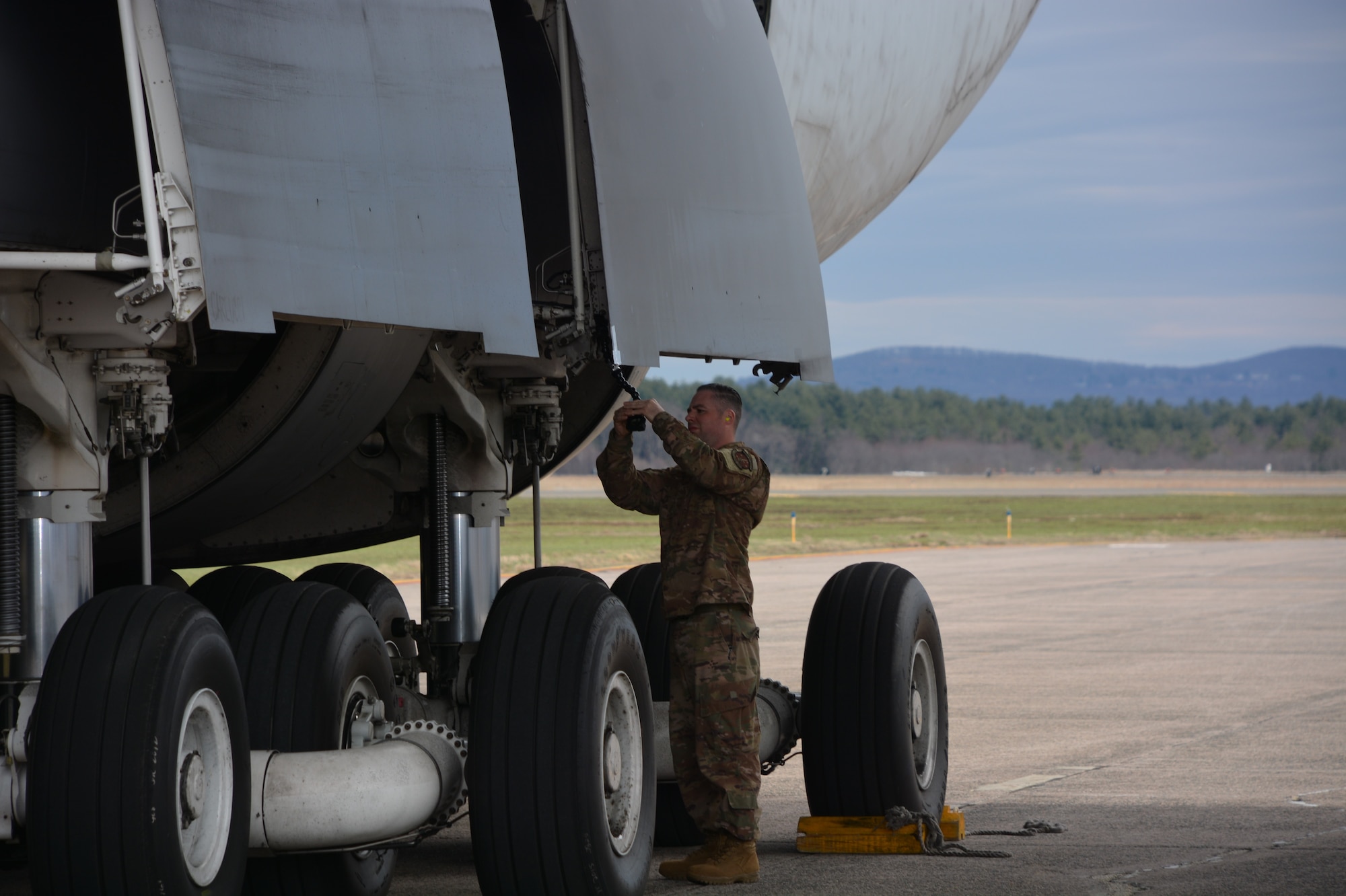 AMCTES Technical Sergeant John Newby adjusts a GoPro video camera on the C-5 aircraft to record outboard tire movement during the C-5 Heavyweight Minimum Radius 180-Degree Turn Tactics Development and Evaluation conducted by AMCTES April 8-12. 2019 at Westover Air Reserve Base in Chicopee, MA.