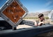 An explosive ordnance disposal technician leans over the back of a truck that contains explosive ordinance.