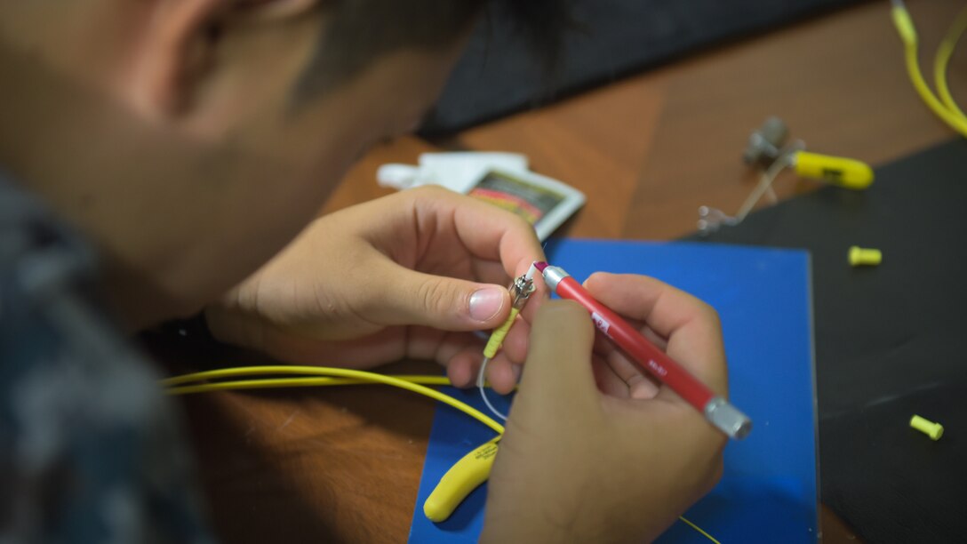 Japan Air Self-Defense Force Sgt. Candidate Shoji Shigeyama, wireline maintenance technician, performs a fiber-optic cable termination exercise at Kadena Air Base, Japan, June 19, 2019.