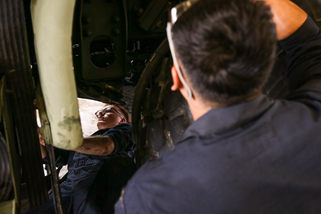 U.S. Marine Corps Cpl. Collin Lourie, left, and Cpl. Sebastian Crossley perform maintenance on a Medium Tactical Vehicle Replacement as part of a Maintenance Support Team on Camp Foster, Okinawa, Japan, June 18, 2019.  The purpose of an MST is to send a team of Marines from outside units to temporarily provide support to units who are in need of manpower in specific Military Occupational Specialties. Lourie, a native of Cambridge, New York, and Crossley, a native of Queenstown, Maryland, are automotive maintenance technicians with Combat Logistics Regiment 35, and were temporarily assigned to an MST to assist Marine Wing Support Squadron 172. (U.S. Marine Corps photo by Sgt. Hailey D. Clay)