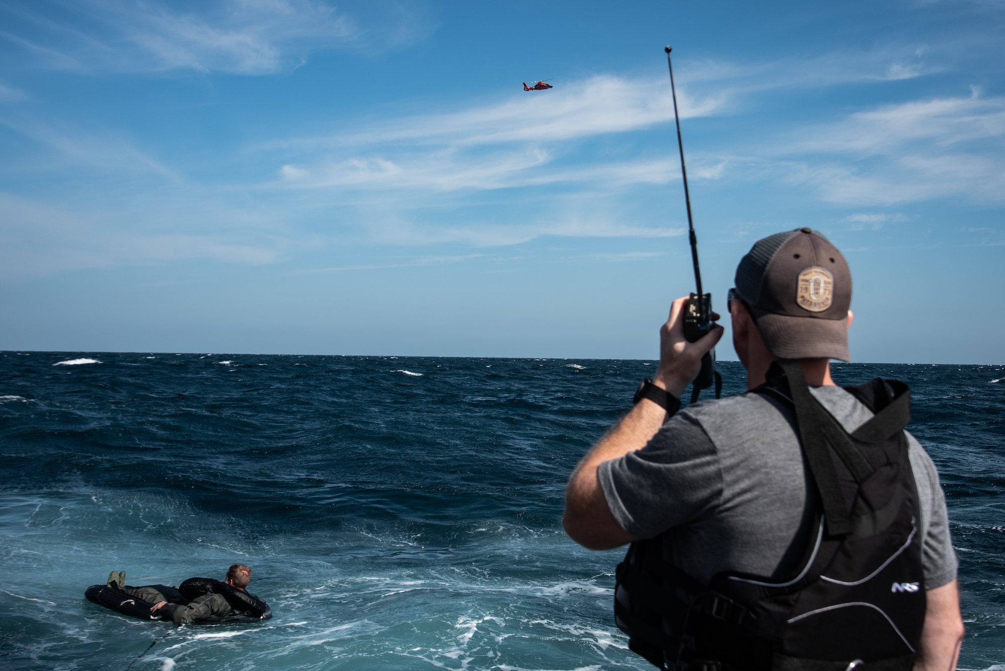 U.S. Air Force Tech. Sgt. David Jones, 20th Operations Support Squadron survival, evasion, resistance and escape noncommissioned officer in charge talks with a U.S. Coast Guard MH-65 Dolphin during a training exercise off the coast of Tybee Island Coast Guard Station, Georgia, June 21.