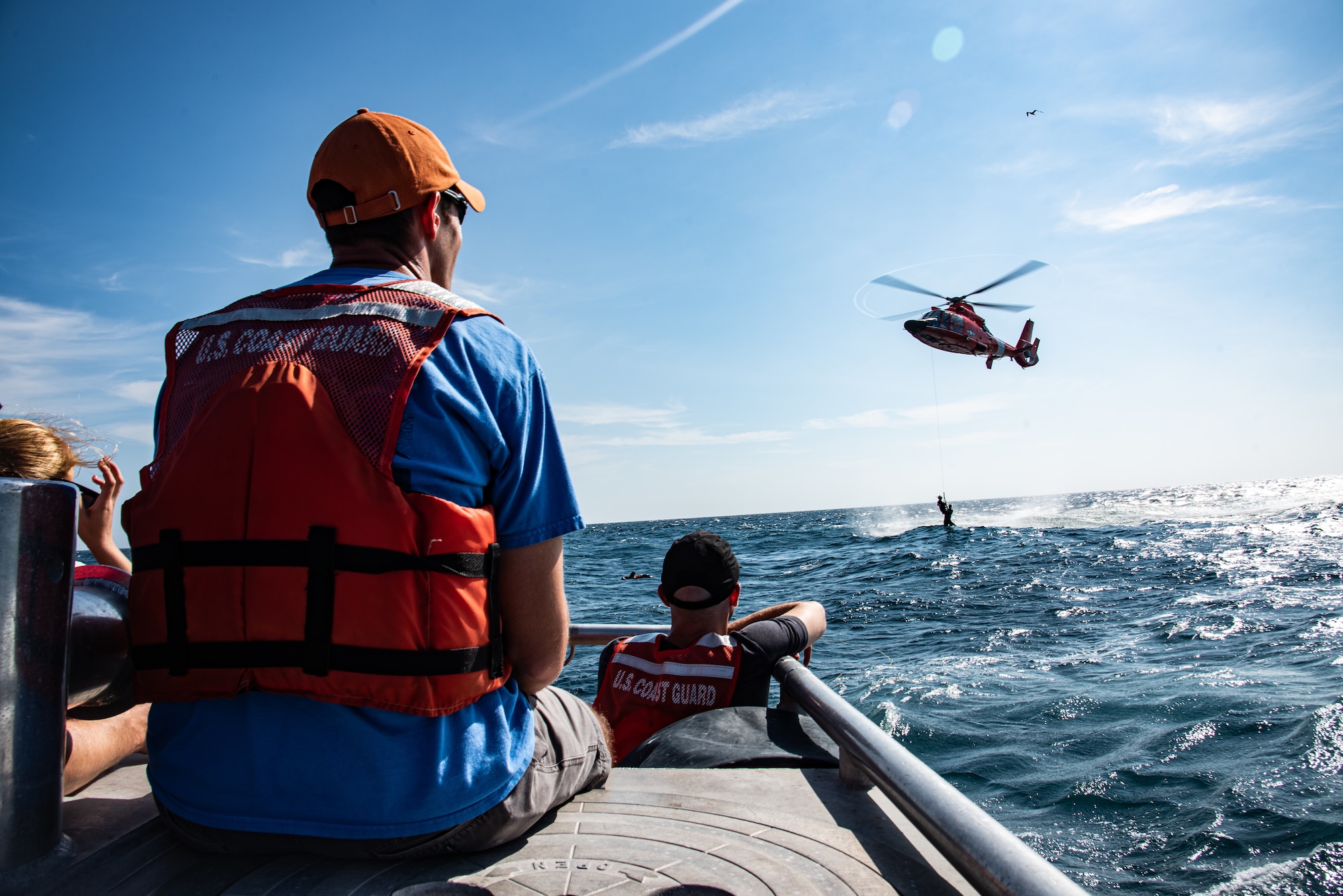 U.S. Airmen and U.S. Coast Guardsmen watch an F-16 pilot be lifted out of the water by a USCG MH-65 Dolphin off the coast of Tybee Island Coast Guard Station, Georgia, June 21. 2019.