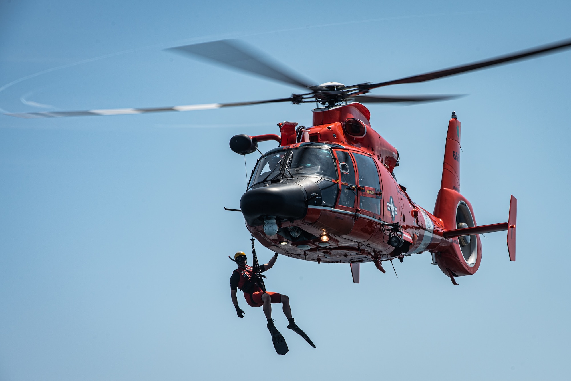 A U.S. Coast Guard (USCG) rescue swimmer hangs of the side of an MH-65 Dolphin off the coast of Tybee Island Coast Guard Station, Georgia, June 21. 2019.