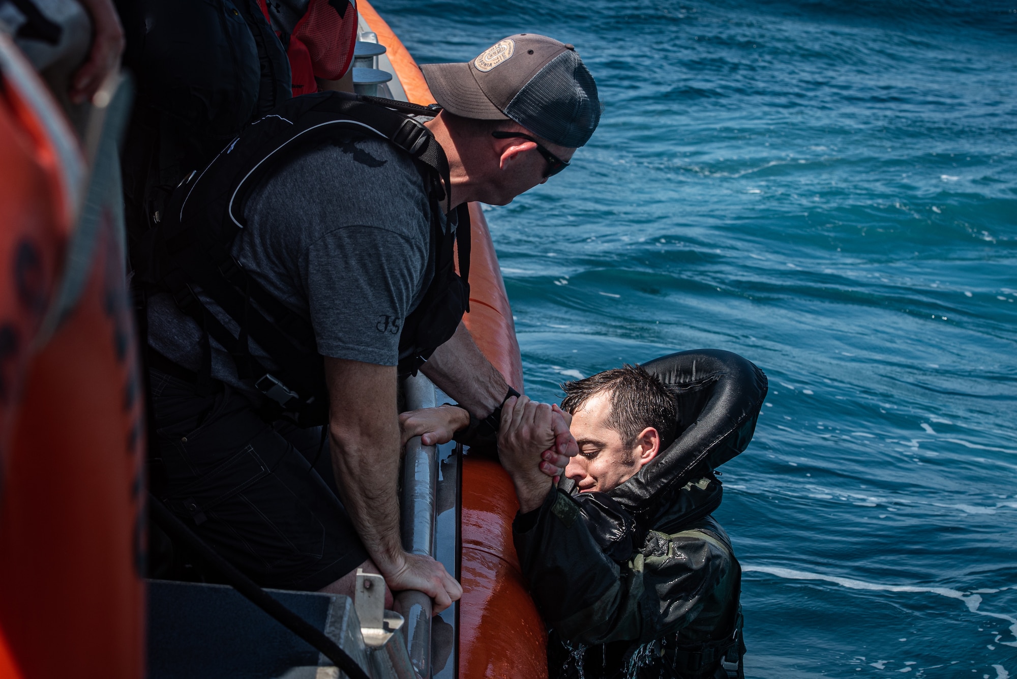 U.S. Air Force Tech. Sgt. David Jones, 20th Operations Support Squadron survival, evasion, resistance and escape non-commissioned officer in charge (left) helps U.S. Air Force Capt. Scott Brandon out of the water off the coast of Tybee Island Coast Guard Station, Georgia, June 21. 2019.