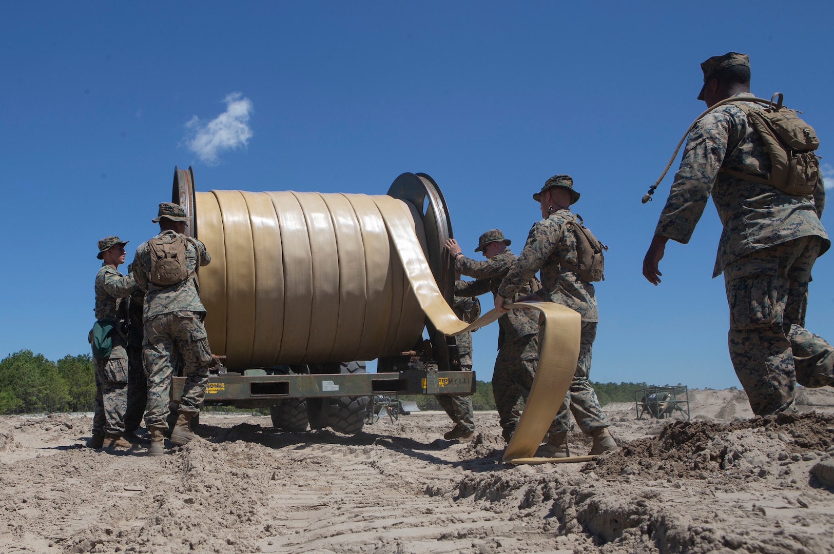 U.S. Marines with Bulk Fuel Company, 8th Engineer Support Battalion, 2nd Marine Logistics Group, utilize a hose-reel system to lay down a fuel line during a Bulk Fuel exercise at Camp Lejeune, N.C., June 19, 2019. The Marines with 8th ESB ran fuel lines, patrolled the fuel sites and provided all around security to remain proficient in fueling support operations. (U.S. Marine Corps photo by Lance Cpl. Adaezia L. Chavez)
