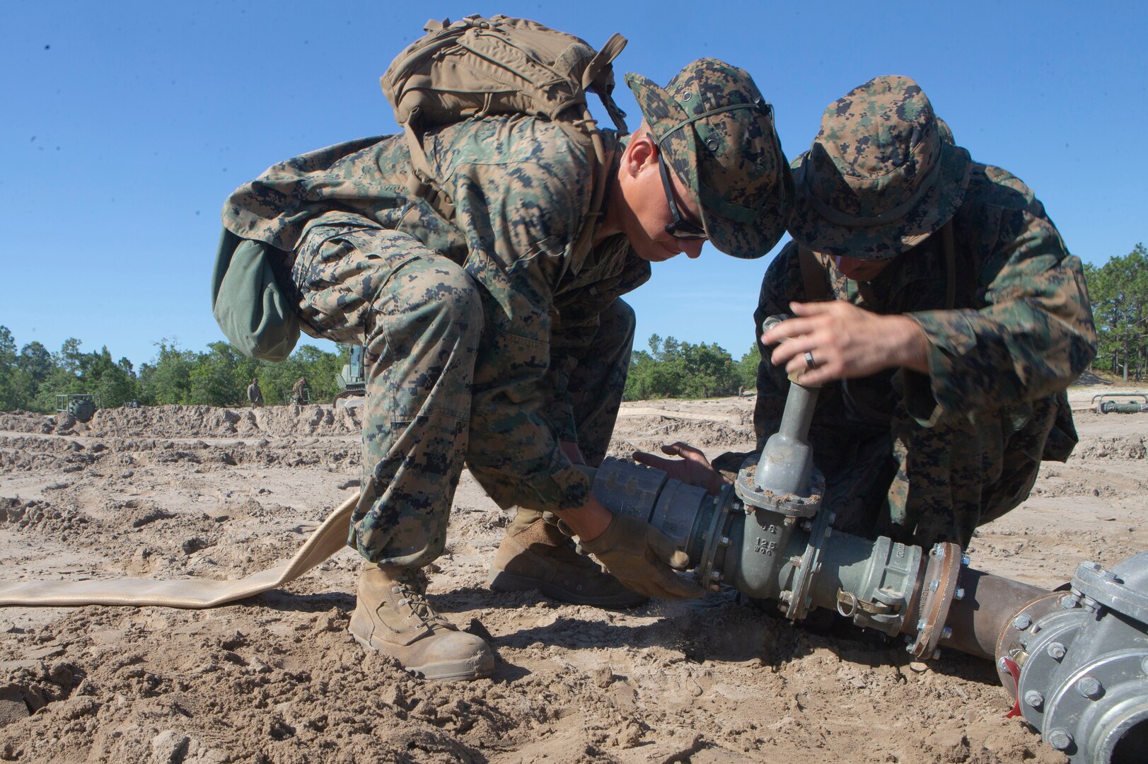 U.S. Marine Corps Lance Cpl. Gabriel Garska, (left) and Lance Cpl. Timothy Weaver, (right) with Bulk Fuel Company, 8th Engineer Support Battalion, 2nd Marine Logistics Group, attach a fuel hose to a gate valve during a Bulk Fuel exercise at Camp Lejeune, N.C., June 19, 2019. The Marines with 8th ESB ran fuel lines, patrolled the fuel sites and provided all around security to remain proficient in fueling support operations.  (U.S. Marine Corps photo by Lance Cpl. Adaezia L. Chavez)