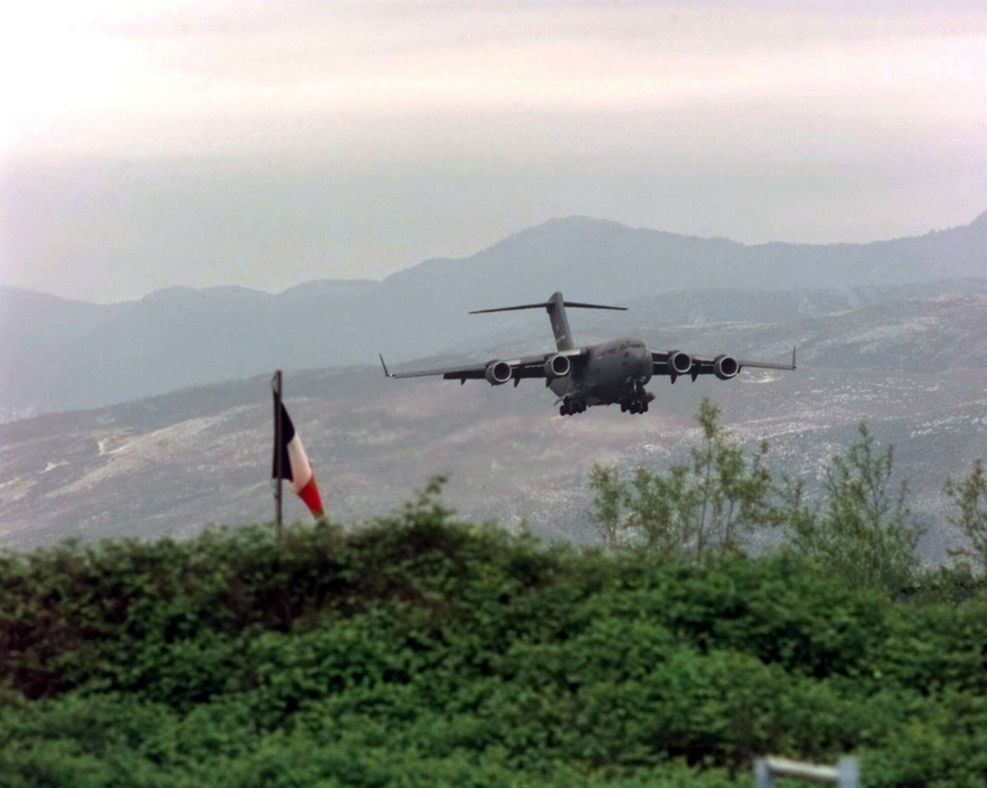 A U.S. Air Force C-17 Globemaster III from Joint Base Charleston makes its final approach to Rinas Airport in Albania during Operation Shining Hope, April 23, 1999. Medical Airmen provided humanitarian support for ethnic Albanian refugees fleeing Kosovo (U.S. Air Force illustration by Tech. Sgt. Cesar Rodriguez)