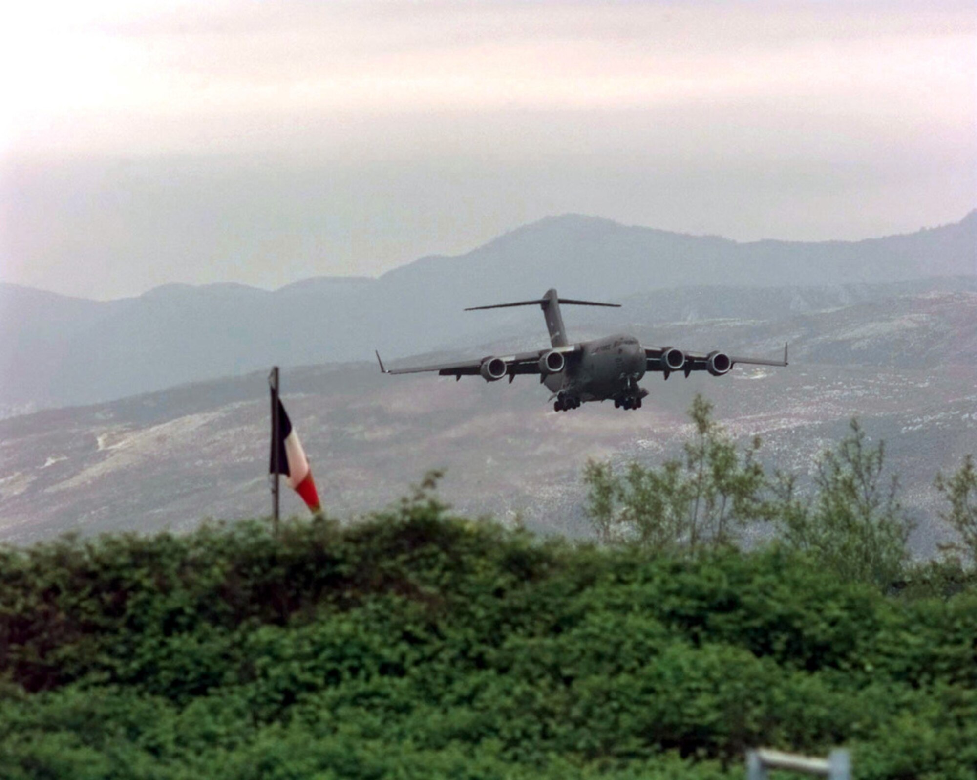 A U.S. Air Force C-17 Globemaster III from Joint Base Charleston makes its final approach to Rinas Airport in Albania during Operation Shining Hope, April 23, 1999. Medical Airmen provided humanitarian support for ethnic Albanian refugees fleeing Kosovo (U.S. Air Force illustration by Tech. Sgt. Cesar Rodriguez)