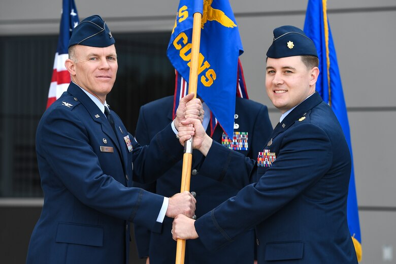 Col. Brian Kehl, 50th Mission Support Group commander, passes the guidon to Maj. Matthew Fleharty, 50th Contracting Squadron commander, during a change of command ceremony in front of the DeKok building at Schriever Air Force Base, Colorado, June 20, 2019. The 50th CONS contractors play a vital role in supporting the 50th Space Wing and Air Force missions by delivering cutting edge acquisition solutions. (U.S. Air Force photo by Kathryn Calvert)