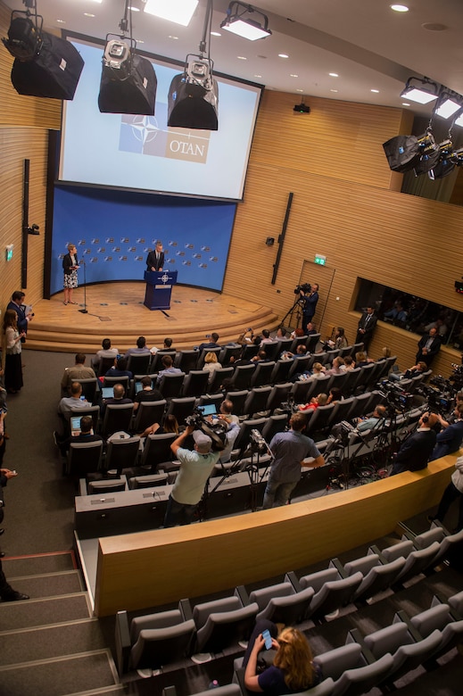 A man in large room speaks at a dias.
