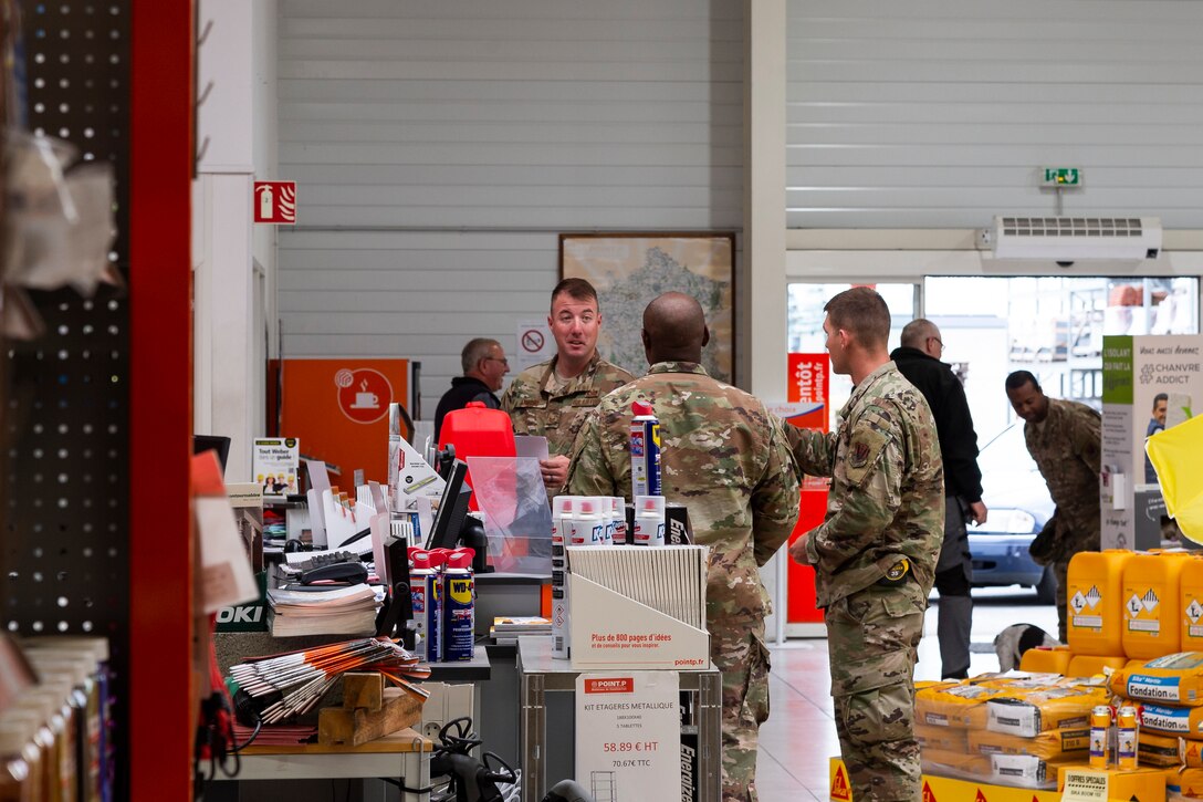 Airmen from the 23d Civil Engineer Squadron discuss purchasing materials, May 31, 2019, near Sainte-Mère-Église, France. The engineers provided structural support for the Commemoration of D-Day 75 by repairing and building bridges that were used to access hard-to-reach areas of a parachute drop zone. As part of the commemoration, parachutists from across the Department of Defense performed the same jumps their predecessors did on D-Day. (U.S. Air Force photo by Airman 1st Class Hayden Legg)