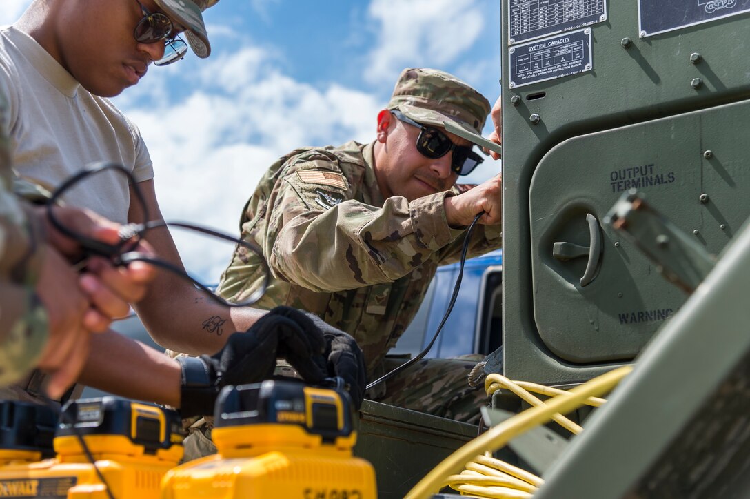 Airman 1st Class Jesse Vega, 23d Civil Engineer Squadron electrical power production engineer, plugs a battery charger into a generator, May 31, 2019, in Sainte-Mère-Église, France. The engineers provided structural support for the Commemoration of D-Day 75 by repairing and building bridges that were used to access hard-to-reach areas of a parachute drop zone. As part of the commemoration, parachutists from across the Department of Defense performed the same jumps their predecessors did on D-Day. (U.S. Air Force photo by Airman 1st Class Hayden Legg)