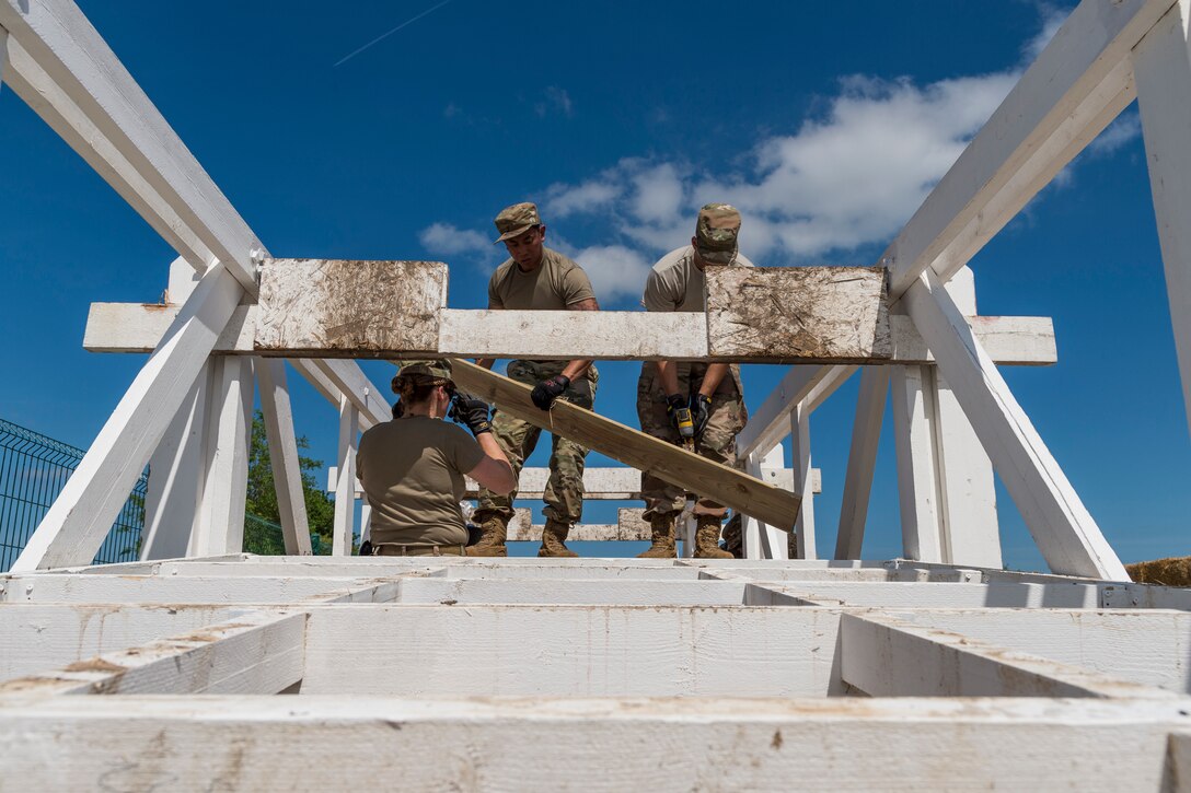Airmen from the 23d Civil Engineer Squadron remove planks from a bridge, May 31, 2019, in Sainte-Mère-Église, France. The engineers provided structural support for the Commemoration of D-Day 75 by repairing and building bridges that were used to access hard-to-reach areas of a parachute drop zone. As part of the commemoration, parachutists from across the Department of Defense performed the same jumps their predecessors did on D-Day. (U.S. Air Force photo by Airman 1st Class Hayden Legg)