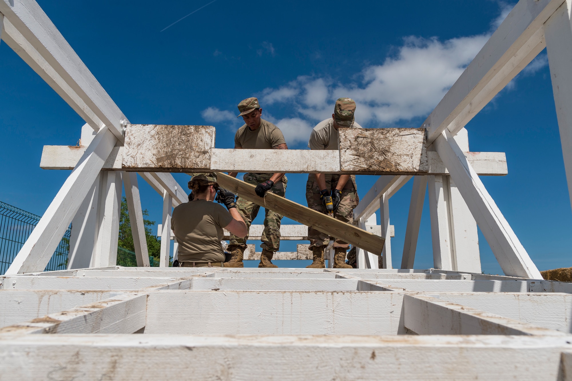 Airmen from the 23d Civil Engineer Squadron remove planks from a bridge, May 31, 2019, in Sainte-Mère-Église, France. The engineers provided structural support for the Commemoration of D-Day 75 by repairing and building bridges that were used to access hard-to-reach areas of a parachute drop zone. As part of the commemoration, parachutists from across the Department of Defense performed the same jumps their predecessors did on D-Day. (U.S. Air Force photo by Airman 1st Class Hayden Legg)