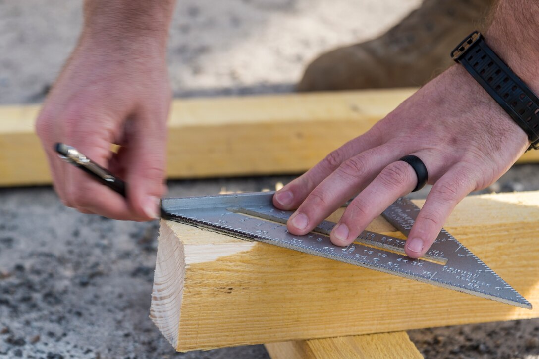 An Airman from the 23d Civil Engineer Squadron marks cuts, June 1, 2019, in Sainte-Mère-Église, France. The engineers provided structural support for the Commemoration of D-Day 75 by repairing and building bridges that were used to access hard-to-reach areas of a parachute drop zone. As part of the commemoration, parachutists from across the Department of Defense performed the same jumps their predecessors did on D-Day. (U.S. Air Force photo by Airman 1st Class Hayden Legg)