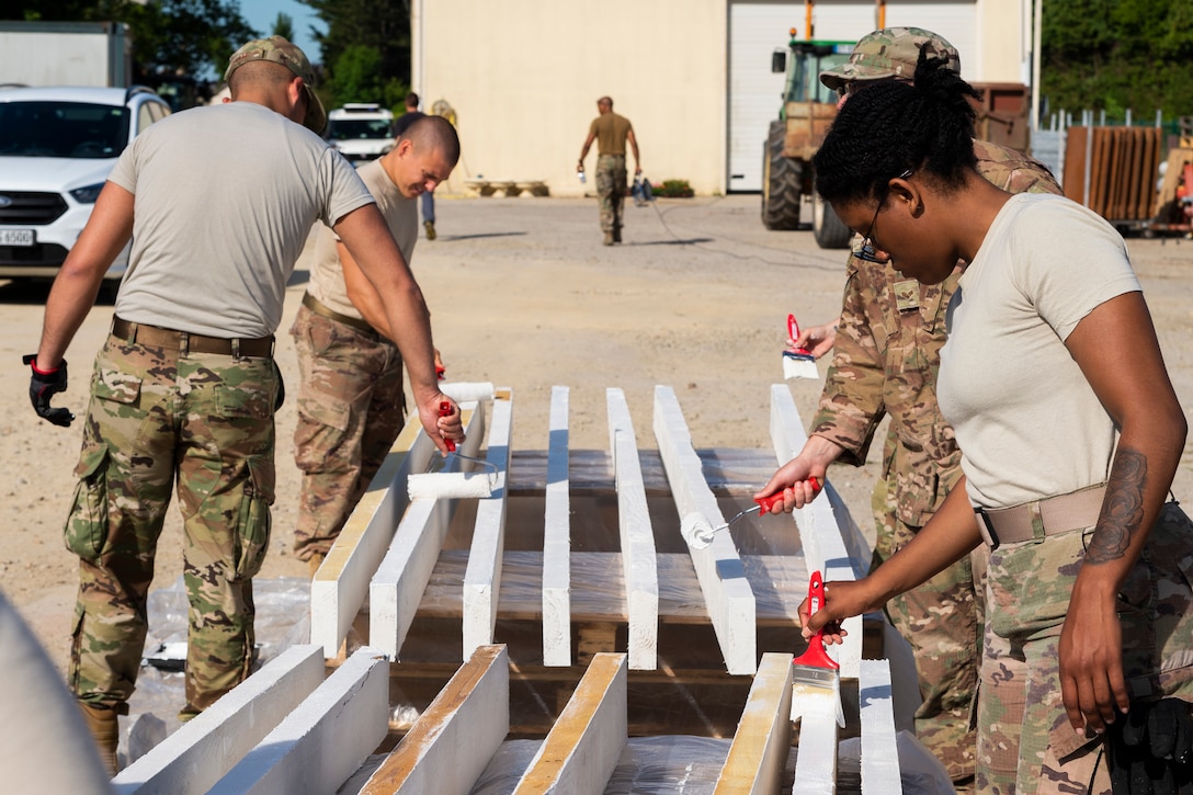 Airmen from the 23d Civil Engineer Squadron and 93d Air Ground Operations Wing paint boards, June 1, 2019, in Sainte-Mère-Église, France. The engineers provided structural support for the Commemoration of D-Day 75 by repairing and building bridges that were used to access hard-to-reach areas of a parachute drop zone. As part of the commemoration, parachutists from across the Department of Defense performed the same jumps their predecessors did on D-Day. (U.S. Air Force photo by Airman 1st Class Hayden Legg)